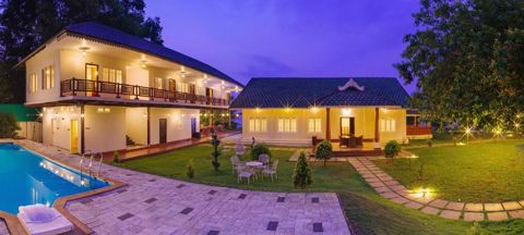 The resort's pool, garden lawn and two buildings lit up at dusk