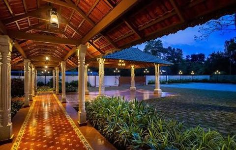A long pillared walkway with a wooden roof and lanterns, beside a lawn