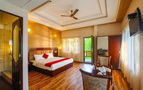 A room with a double bed, wooden floor, armchairs and a door to a balcony