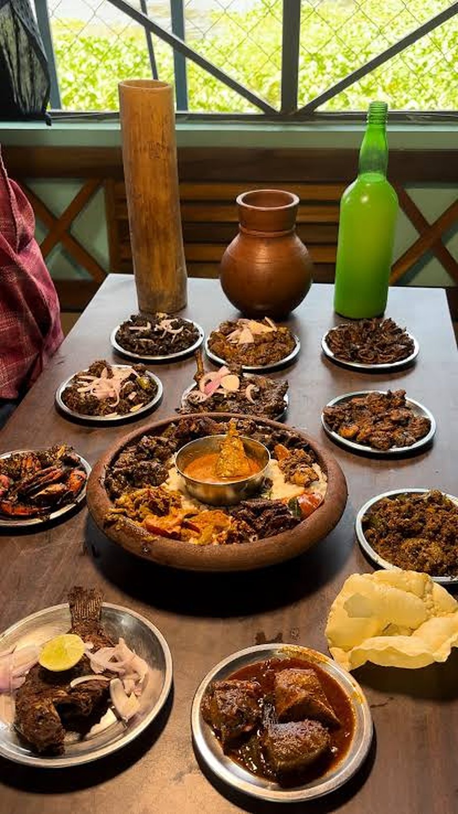 A table of Kerala dishes around a clay pot centrepiece, with appam and a clay pot of toddy