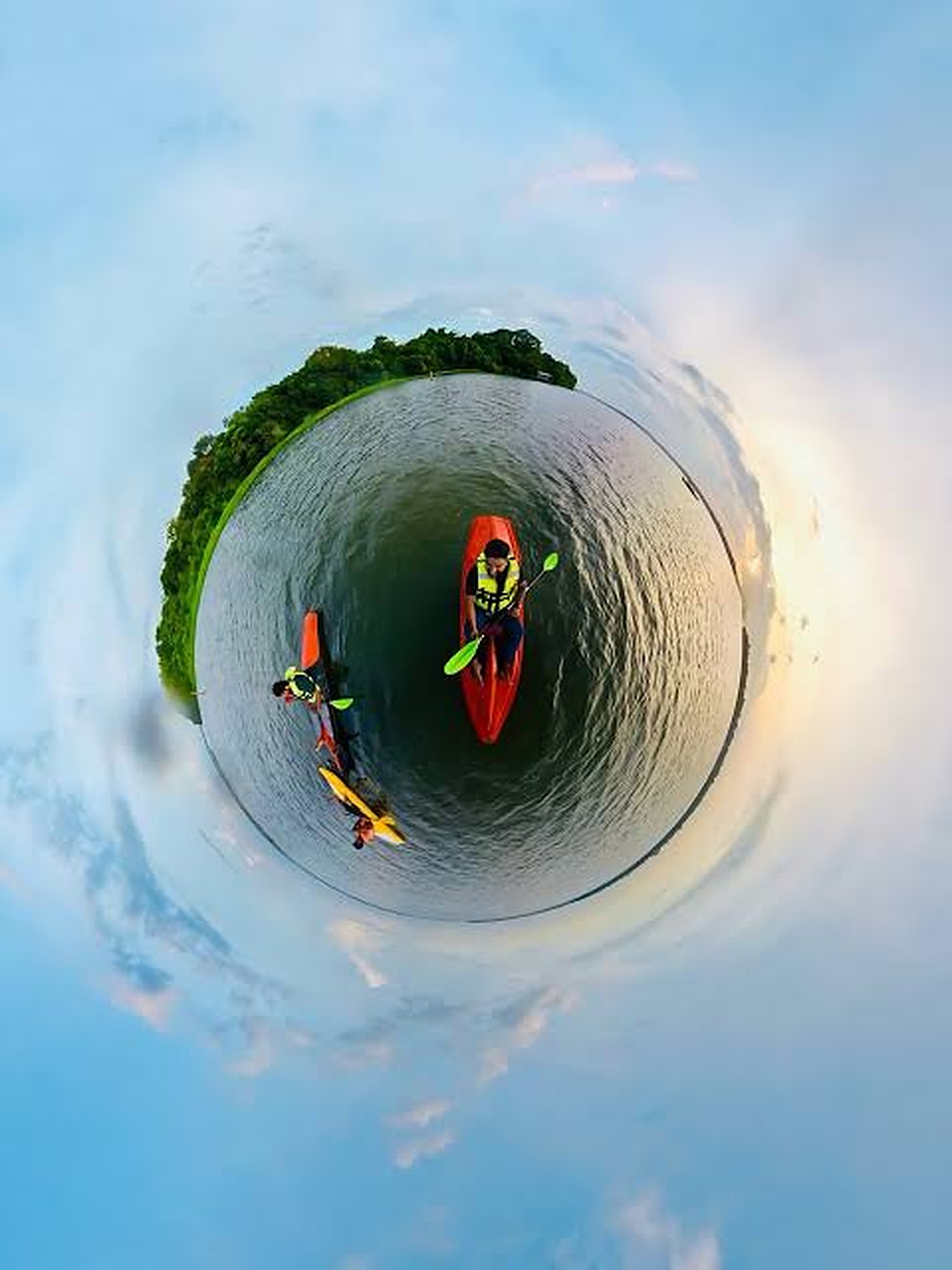 Two kayaks on the lake seen in a round, little-planet view with the green shore curving around them