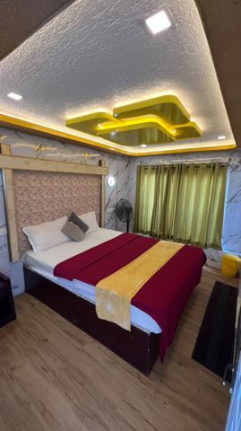 A bedroom with a double bed, marble-look walls and a glowing gold ceiling light