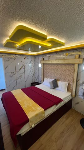 A bedroom with a padded headboard, marble-look walls and a gold-lit ceiling