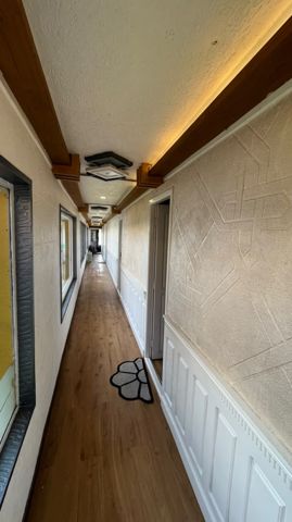 A corridor with a wooden floor, panelled walls and warm lighting