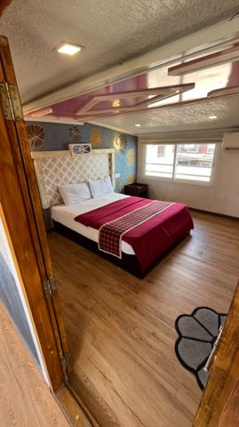 A bedroom with a double bed, a lattice headboard, patterned walls and a window
