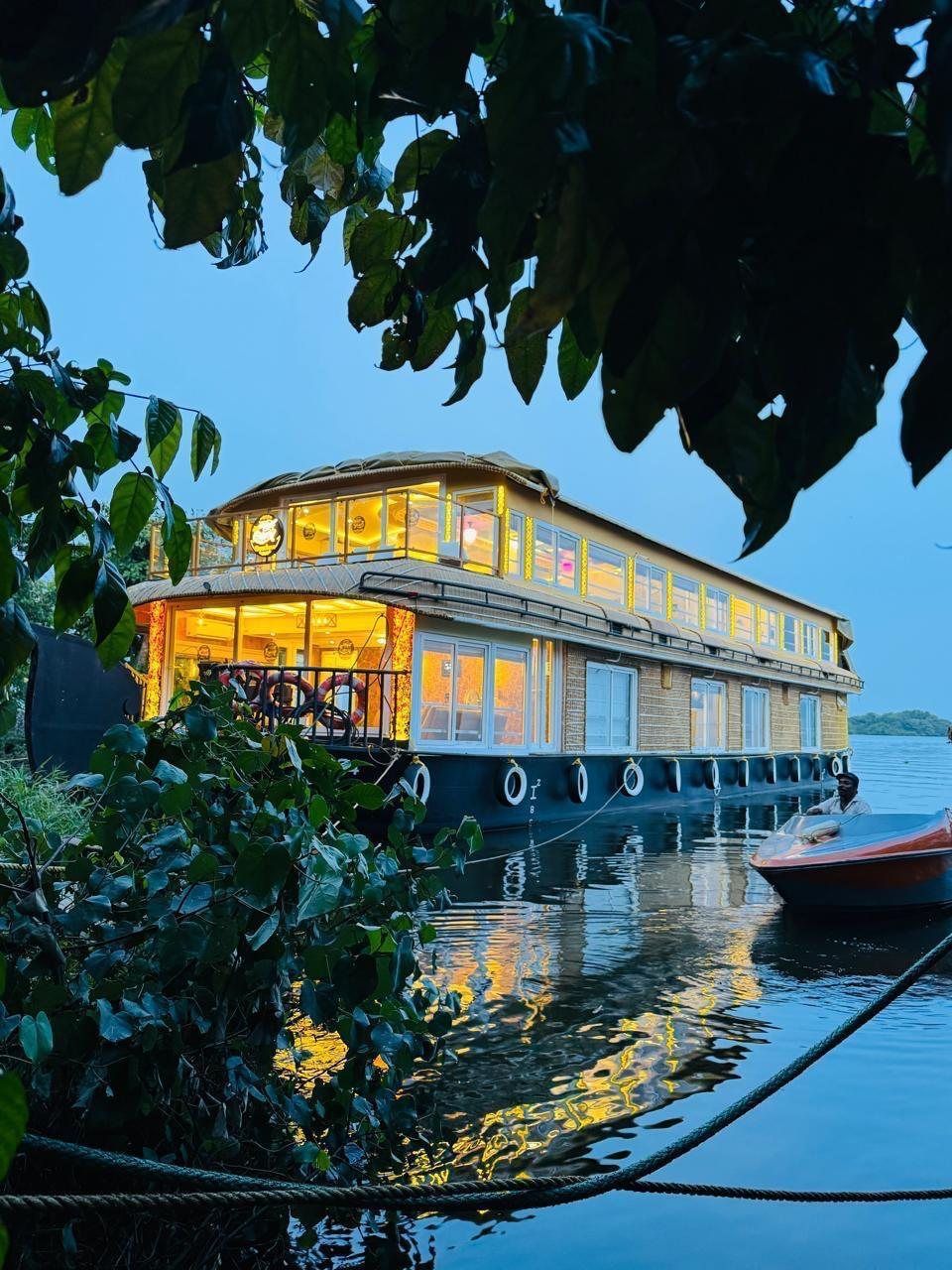Royal Queen Roxxlana glowing at dusk with a speedboat alongside, seen through the leaves