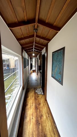A corridor with a wooden ceiling and windows onto the water