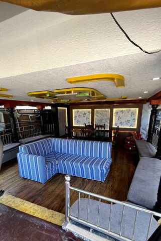 A lounge with a blue striped sofa and a dining table under a decorated ceiling