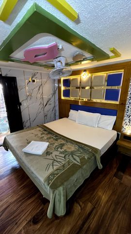A bedroom with a double bed and a lit, padded headboard