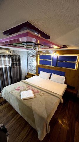 A bedroom with a double bed, a blue headboard, curtains and an air-conditioner