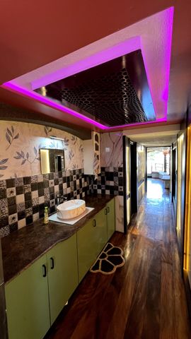 A wash basin on a long counter with patterned tiles, beside the corridor