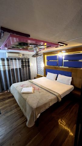A bedroom with a double bed, blue headboard panels and an air-conditioner