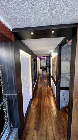 A lit corridor with a polished wooden floor leading to the rooms