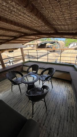 A shaded upper deck with a woven roof, wicker chairs and cushioned seating