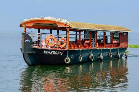 A slow boat with a thatched roof, wooden railings and life rings cruising on calm water